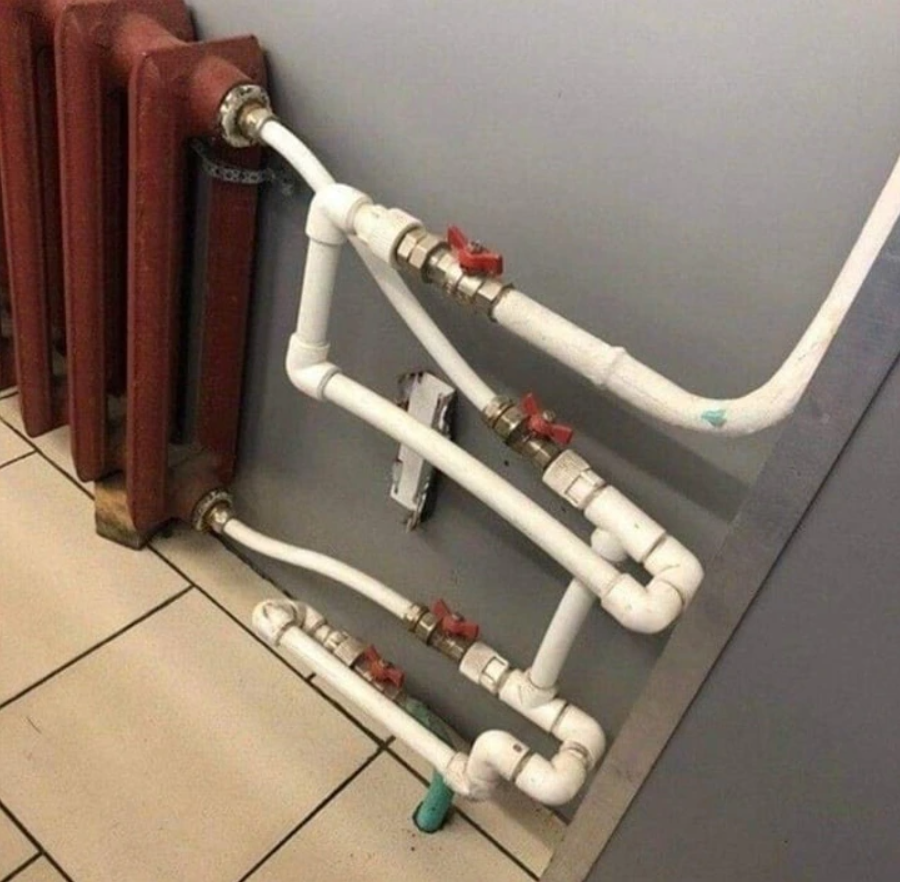 Komplexný systém radiátorových potrubí s ventilmi vedľa steny a dlaždicovej podlahy.