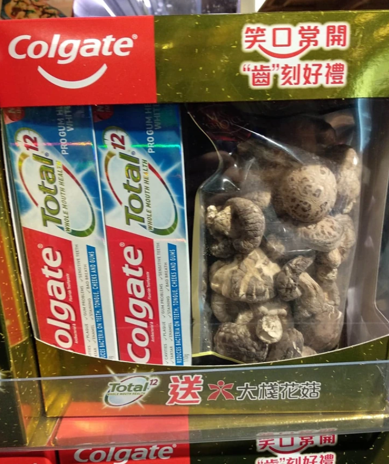 Krabica so zubnou pastou Colgate Total a sušenými hubami v balení spolu na pultovom displeji.