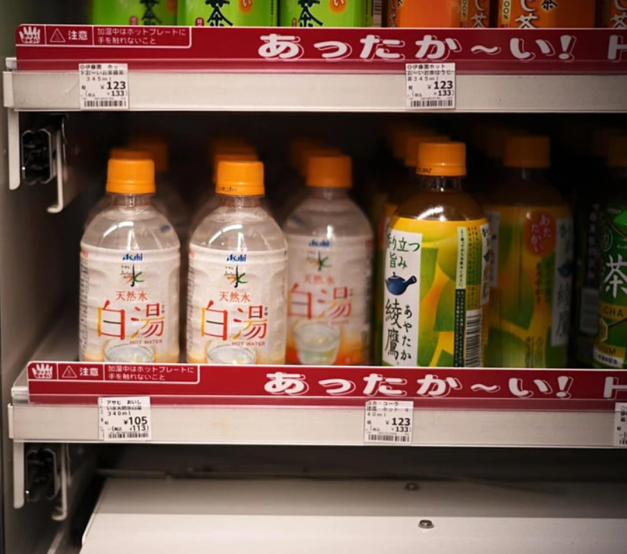 Fľaše nápojov s japonskými etiketami v regáli obchodu.