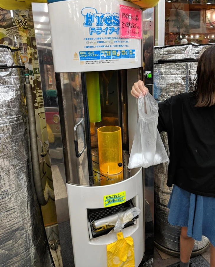 Osoba vedľa automatu na suchý ľad s taškou plnou ľadových kociek pripravených na použitie.