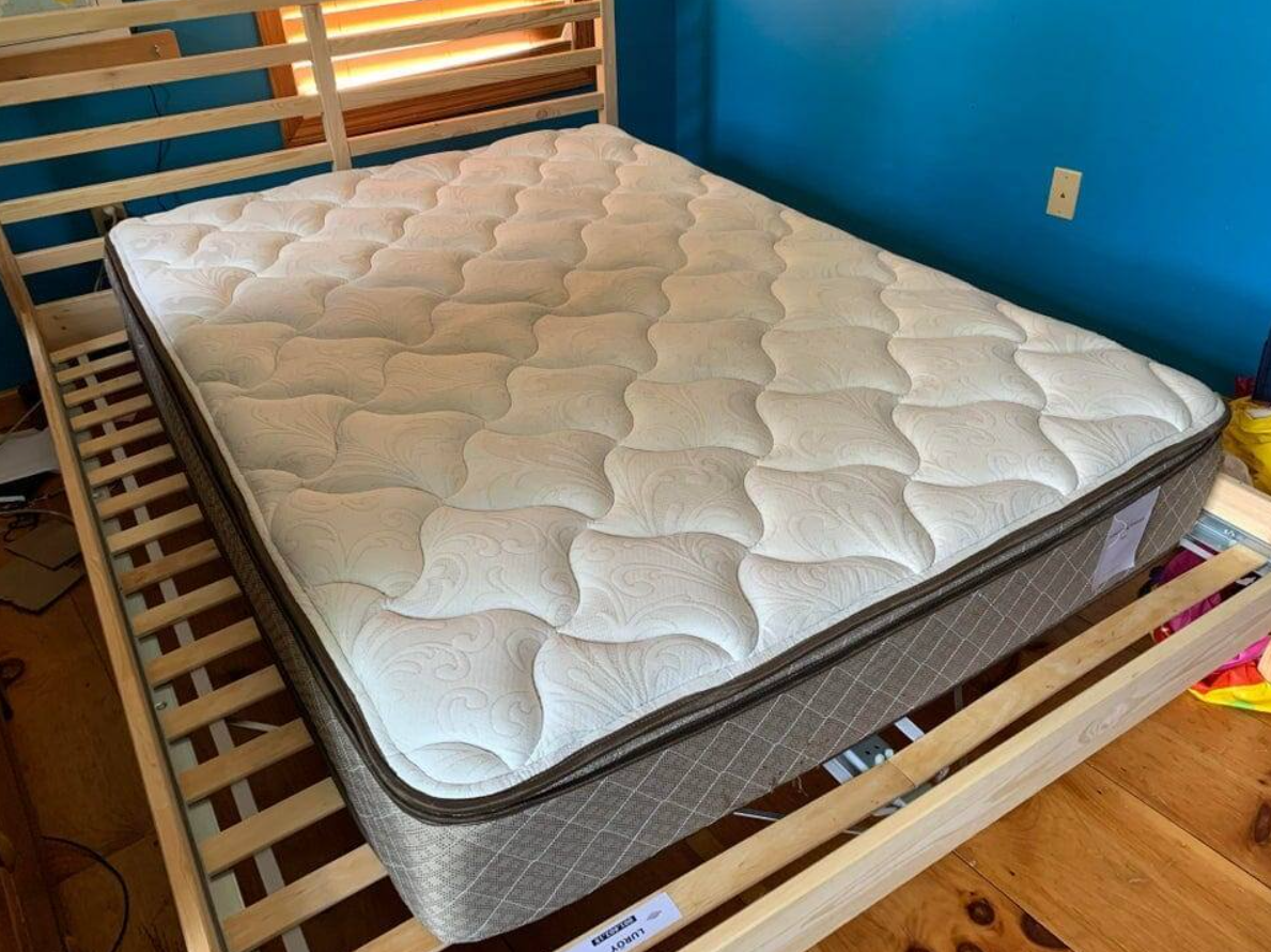 Pohodlný matrac na drevenom rámovom posteli v modrej izbe, pripravený na kvalitný spánok.