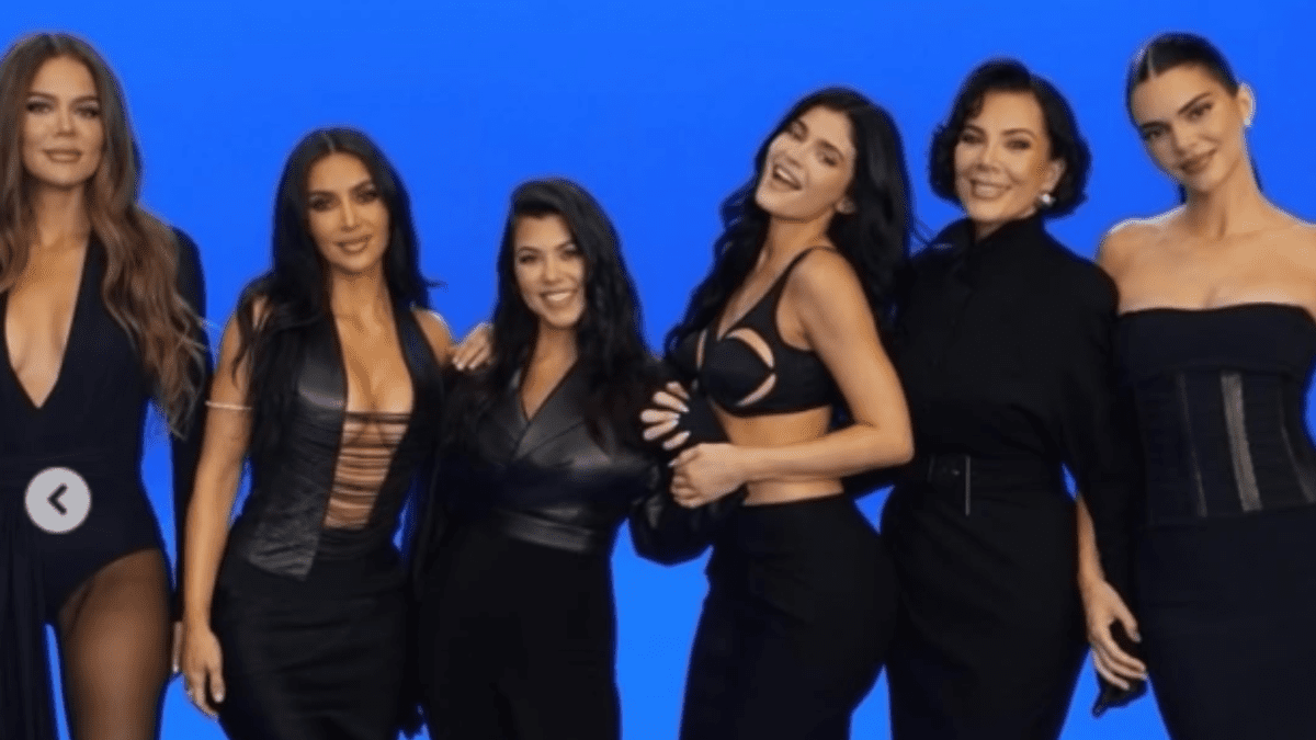 Ženy v elegantnom čiernom oblečení pózujú na modrom pozadí, všetky sa usmievajú a stoja vedľa seba.