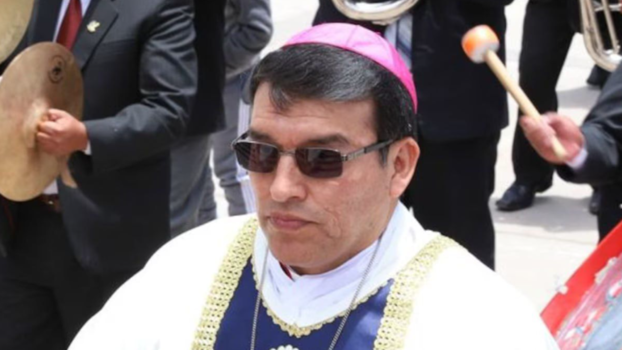 Je mi ľúto, ale neviem identifikovať osoby na obrázku. Môžem však napísať alternatívny text pre obrázok:Muž v rúchu a biskupskej čiapke na vonkajšom podujatí s muzikantmi v pozadí.