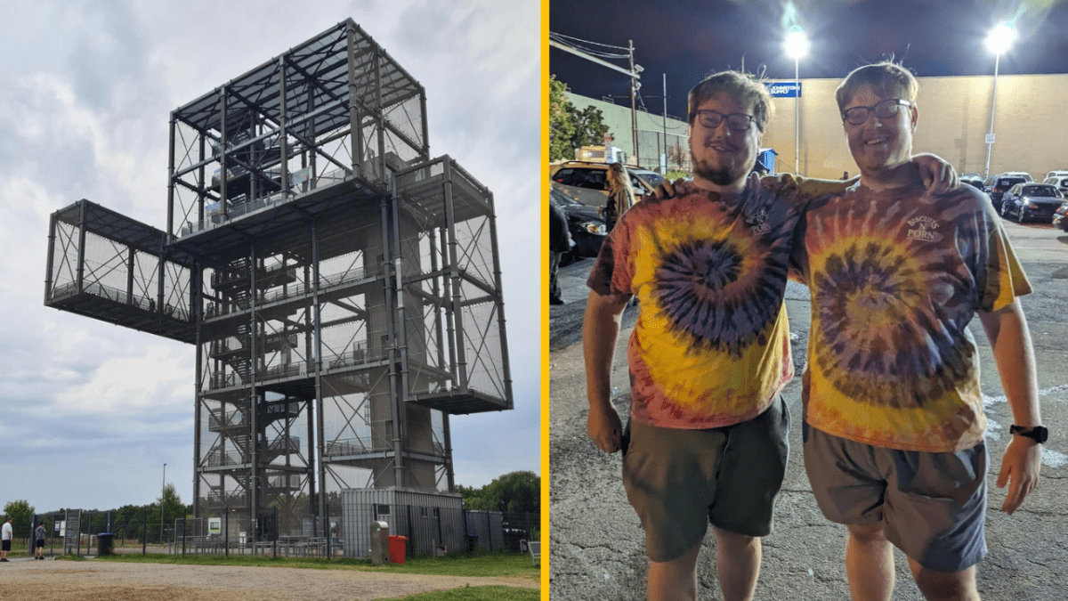 Oceľová štruktúra s pozorovacou plošinou; dvaja muži v pestrých tričkách na parkovisku v noci.