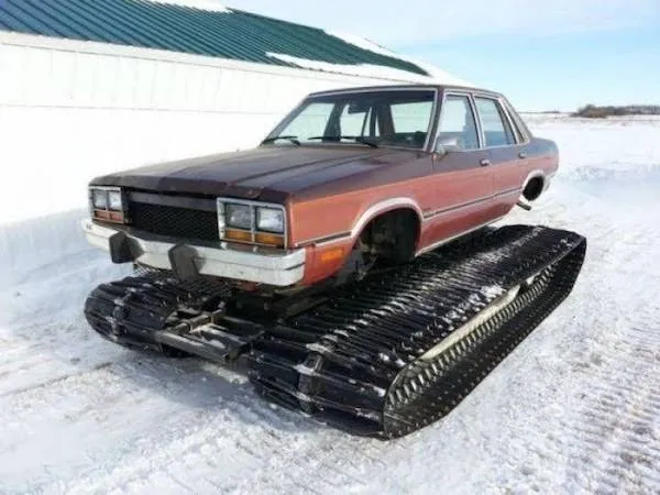 Auto na pásoch v zasneženej krajine, kombinácia klasického sedanu a pásového podvozku pre zimné podmienky.