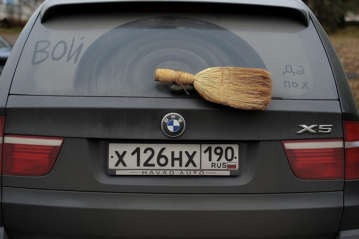 Auto BMW X5 s metlou pripevnenou vzadu na prašnom okne, ktoré bolo čistené kruhovým pohybom.