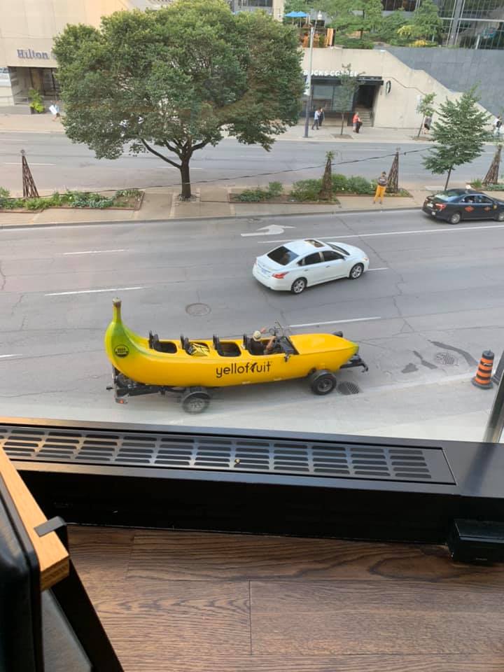 Auto v tvare banánu jazdí po ulici, vedľa neho idúce autá.