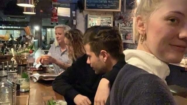 Skupina priateľov sedí pri bare v reštaurácii, baví sa a užíva si večer.