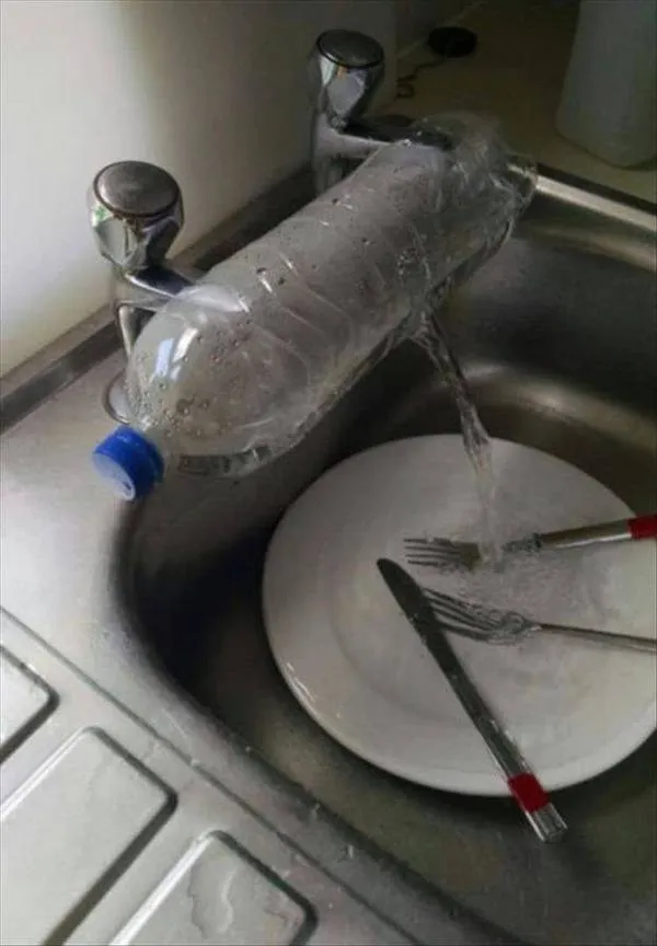 Plastová fľaša na vodu improvizovaná ako kohútik umýva riad v kuchynskom dreze.