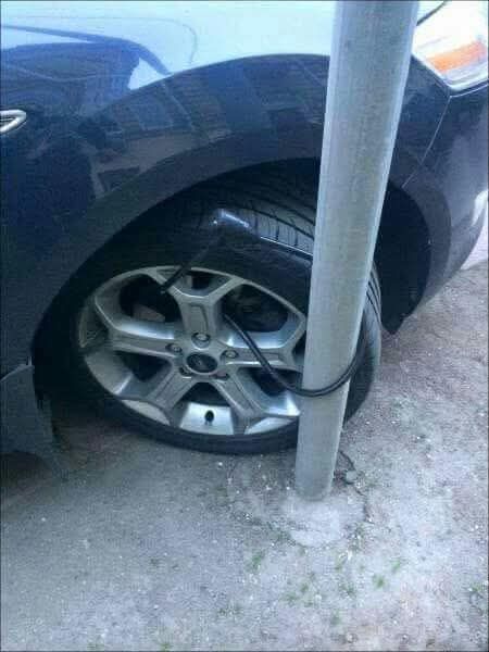 Auto zaparkované s nezvyčajným zabezpečením pneumatiky zamknutej okolo stĺpa.