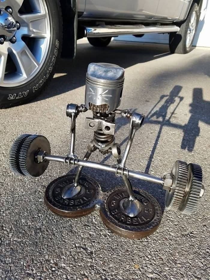 Robot z kovových súčiastok ako činka na ceste, kreatívna recyklácia mechanických dielov.