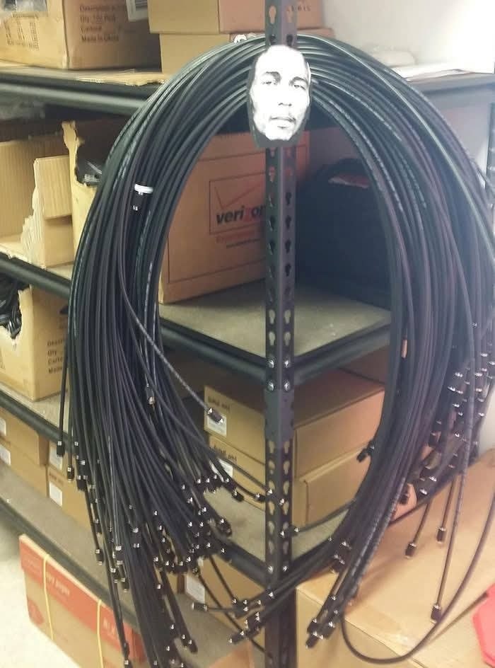 Polica v sklade s navinutými káblami a krabicami v pozadí.