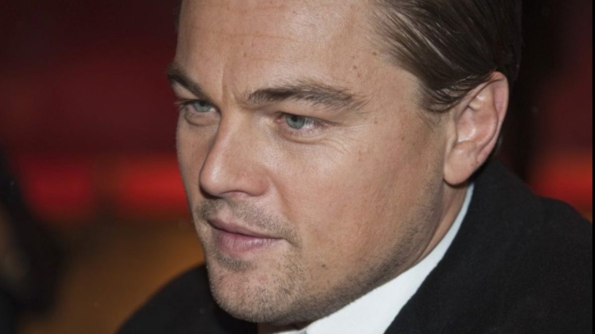 Osoba v obleku s elegantným vzhľadom na červenom pozadí, detailný portrét z profilu.