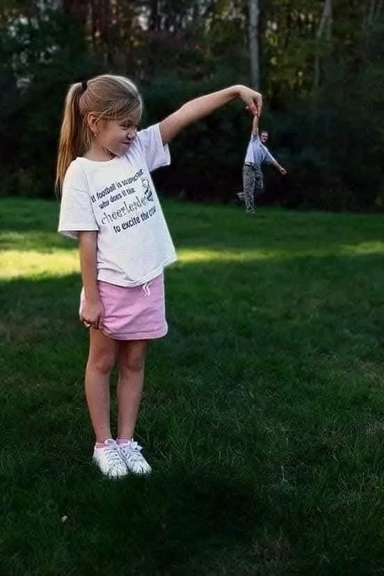 Dievča drží malú postavičku na trávniku, optická ilúzia s perspektívou.