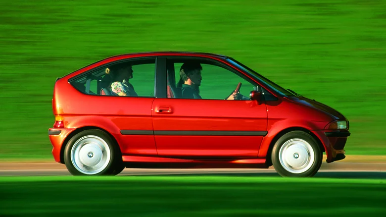 Červené auto v pohybe na rozmazanom zelenom pozadí, bočný pohľad.