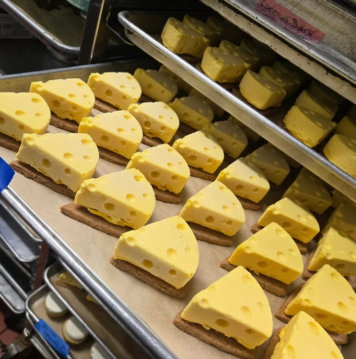 Výstavka sušienok v tvare syra, uložených na plechu vo viacerých radoch, pripravených na servírovanie.