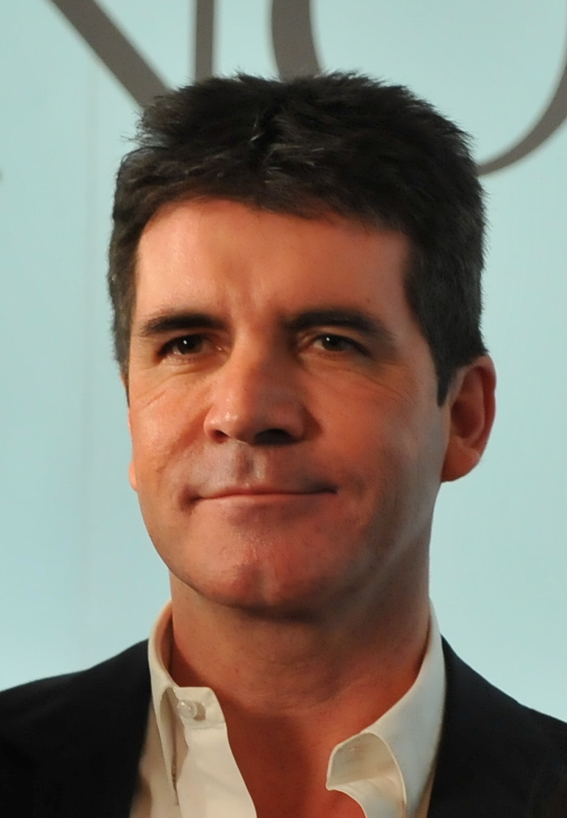 Prominentný muž v obleku s neutrálnym výrazom tváre, svetlá modrá pozadie, formálne oblečený.