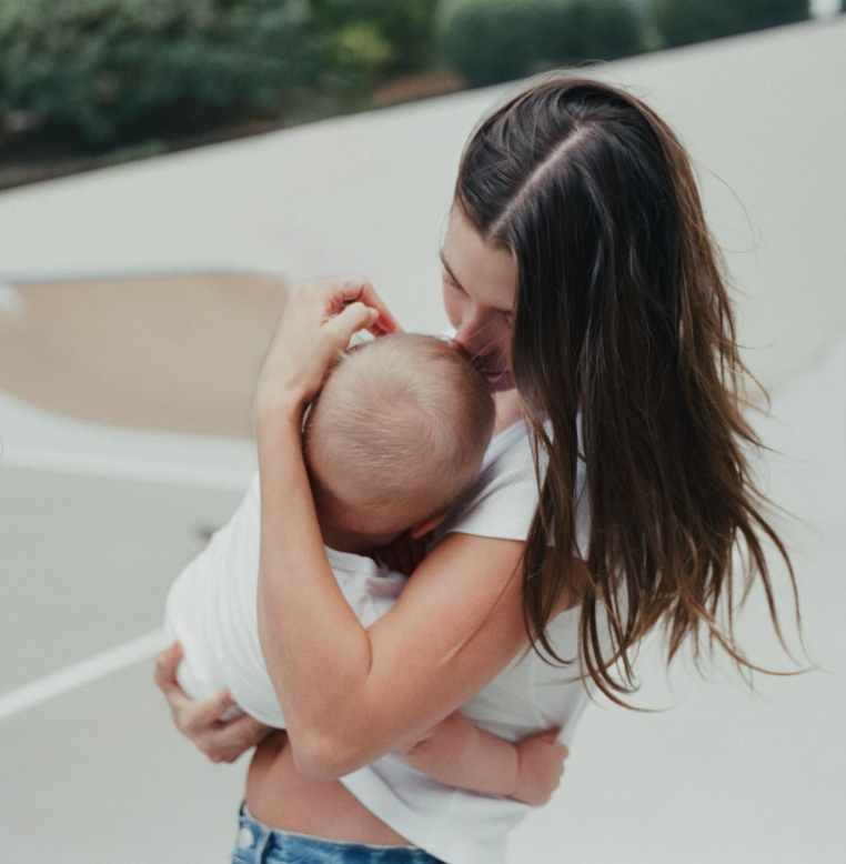 Matka láskyplne objíma dieťa vonku na slnečnom dni.