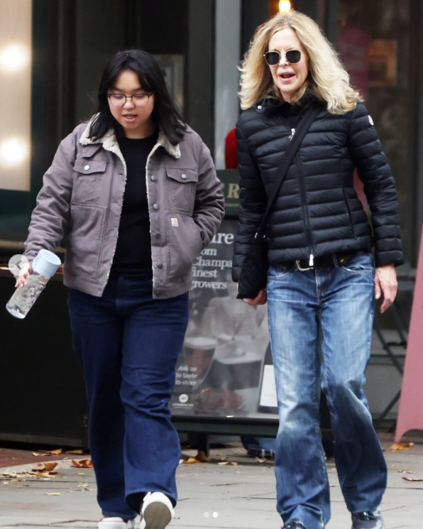 Dve ženy kráčajú po ulici v zimných bundách, jedna nesie fľašu s vodou.