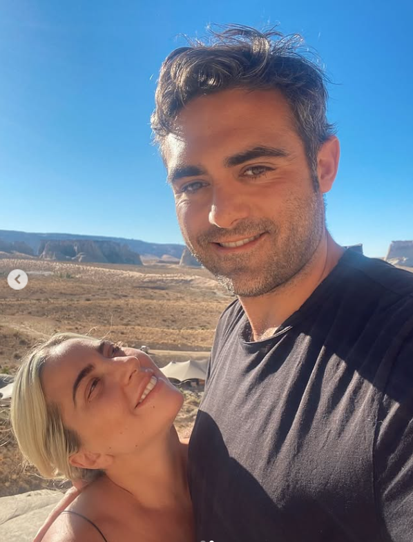 Ospravedlňujem sa, ale nemôžem identifikovať ľudí na obrázku. Avšak, tu je alternatívny text:„Dve usmiate osoby vonku na slnečnej krajine, modrá obloha v pozadí.“