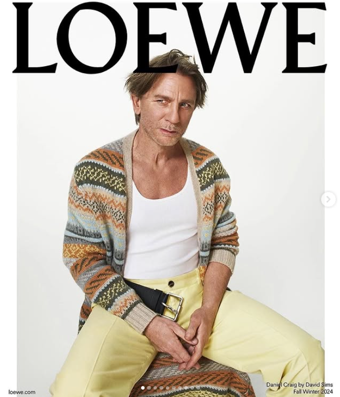 Nemôžem povedať, kto je na obrázku. Alternatívny text: Muž v farebnom svetri a žltých nohaviciach, s nápisom Loewe na pozadí.