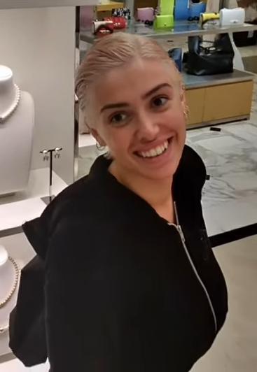 Osoba v obchode s luxusnými šperkami sa usmieva pri vitríne s náhrdelníkmi.