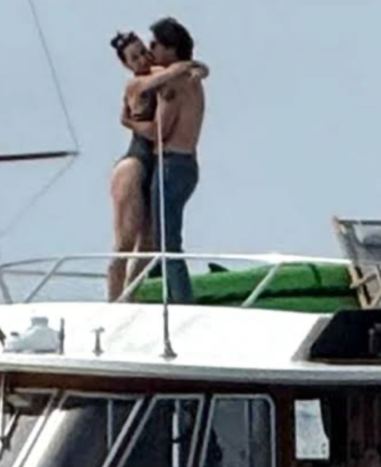 Dvojica objímajúca sa na palube jachty počas slnečného dňa pri mori.