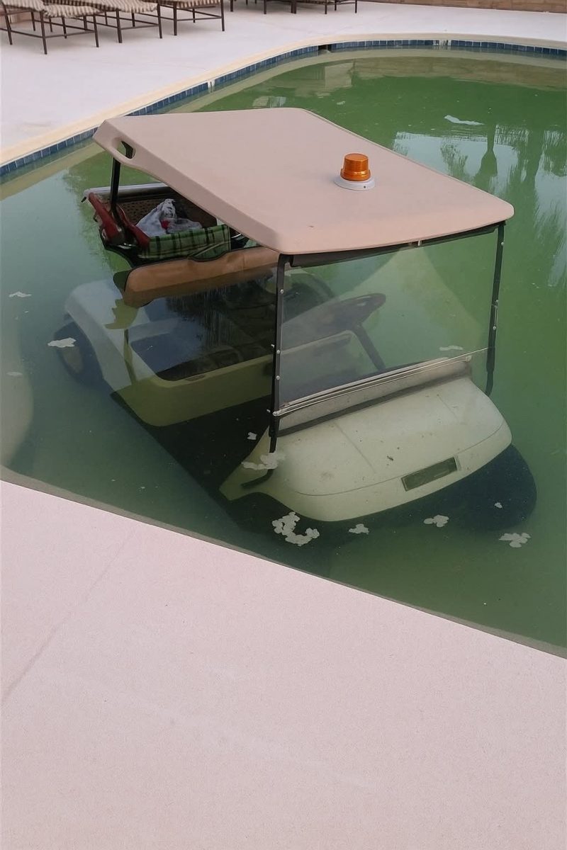 Golfové vozítko čiastočne ponorené v bazéne, obklopené zelenou vodou.