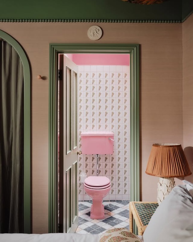 Ružovo-zelená retro kúpeľňa s toaletou v štýle vintage, zdobená dlaždicami a dekoračnými prvkami.