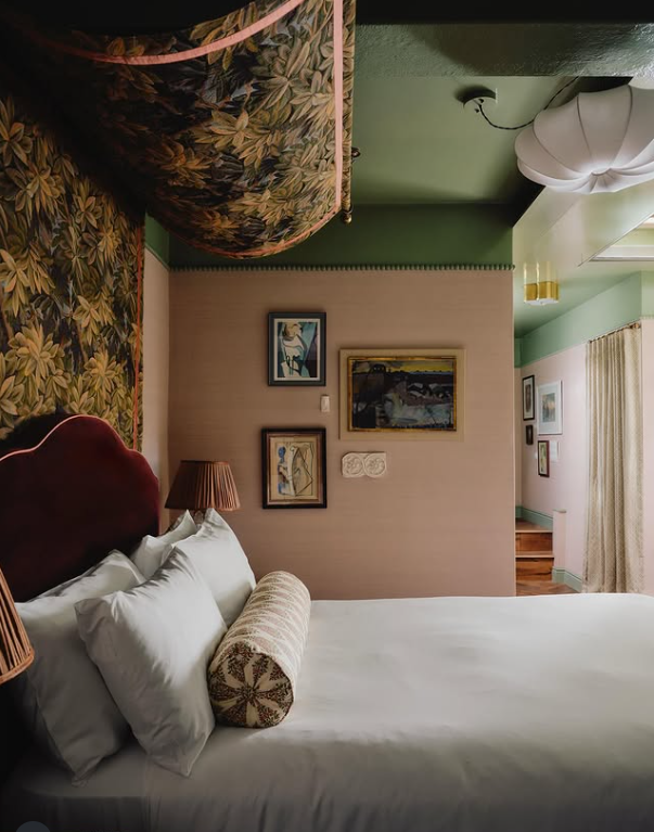 Štýlová hotelová izba s kvetinovou tapetou, obrazmi a pohodlnou posteľou, vytvárajúca útulnú atmosféru na relaxáciu.