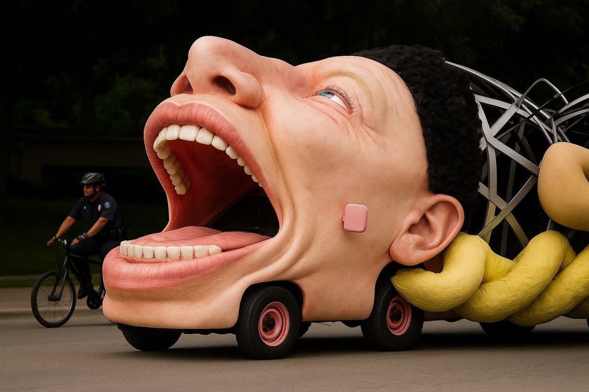 Veľká socha hlavy na kolesách na ulici, vedľa prechádza cyklista v uniforma.