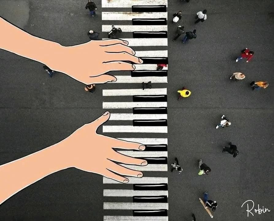 Ruky hrajú na prechode pre chodcov, ktorý vyzerá ako klavírová klávesnica, s ľuďmi prechádzajúcimi cez cestu.