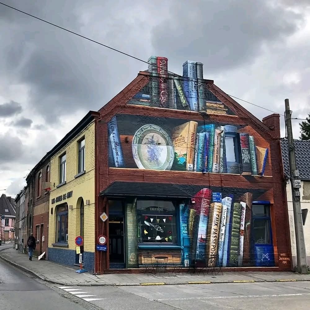 Budova s veľkolepým muralom kníh na stene, zdôrazňujúci kreatívny mestský dizajn.