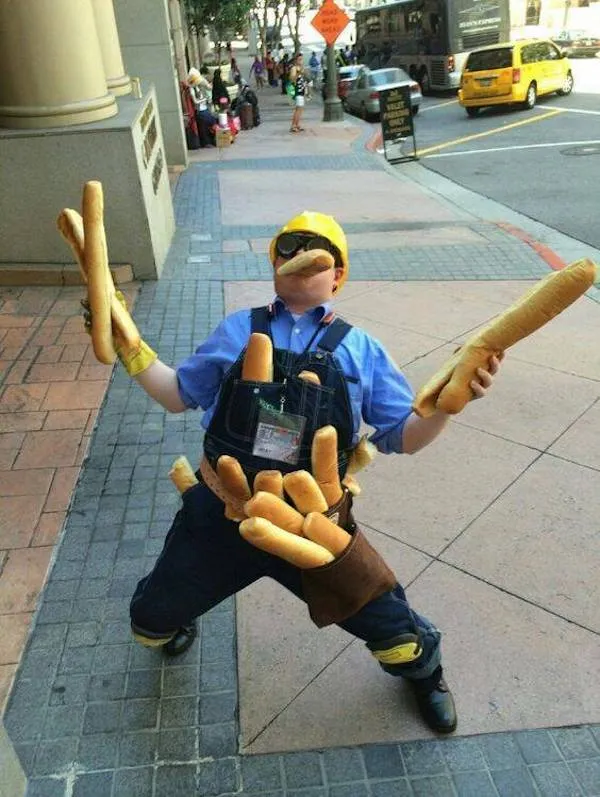Osoba v stavebnej prilbe žongluje s bagetami na mestskej ulici, kreatívne oblečenie a póza.