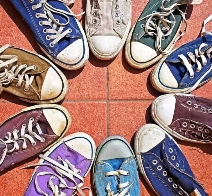 Rôznofarebné tenisky usporiadané v kruhu na červenej dlážke.