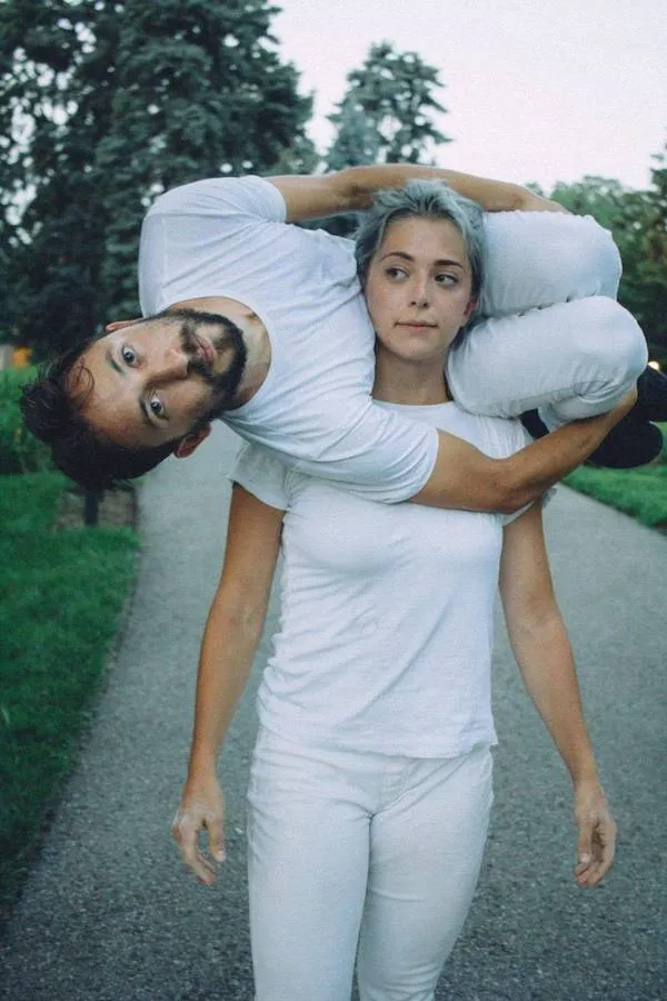 Dvaja ľudia v bielom oblečení počas zábavného cvičenia na chodníku v parku.