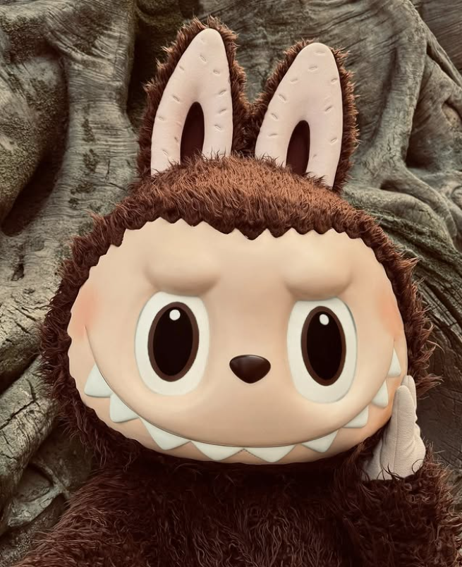 Kreatívna postava s huňatým kostýmom a ušami, stojaca pred textúrovaným pozadím.