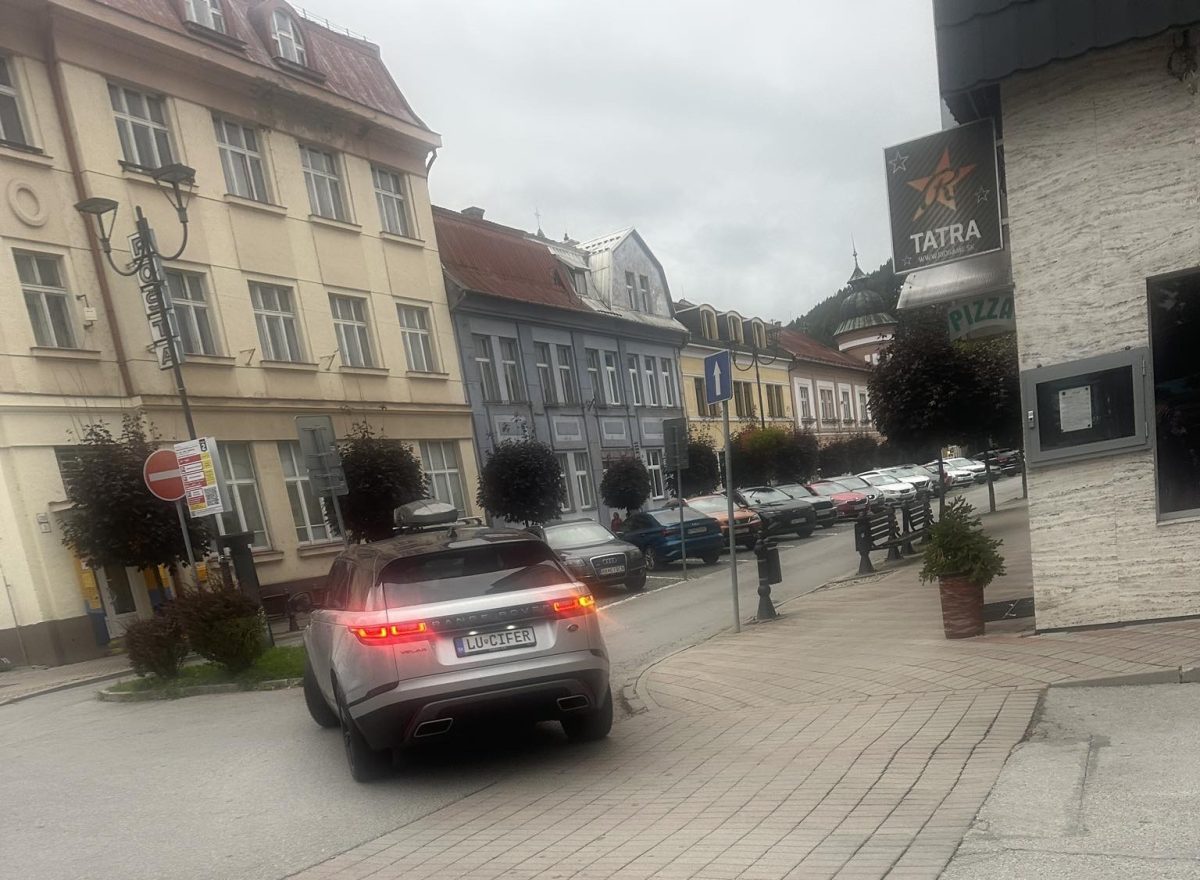 Mesto so starobylými budovami, auto s evidenčným číslom LU-CIFER jazdí po ulici.