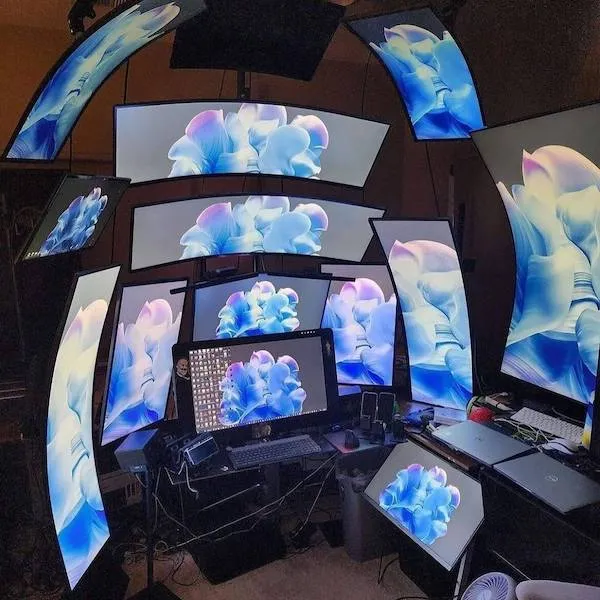 Množstvo obrazoviek s modrou kvetinovou témou, usporiadané okolo pracovného stola s počítačom.