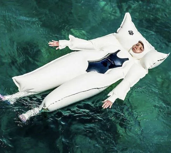 Osoba vo vankúšovom obleku vo vode, plávajúca na hladine.