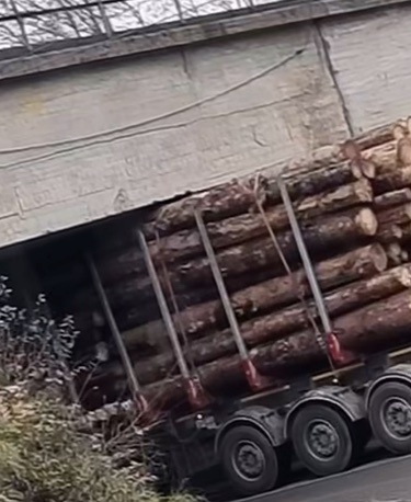 Nákladné auto nesie drevá pod mostom s príliš nízkou výškou, čo spôsobuje zablokovanie.