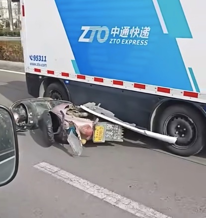 Skúter prevrátený na ceste vedľa kamióna čínskej kuriérskej služby ZTO Express.