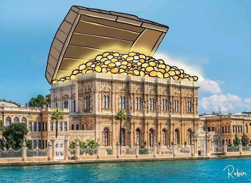 Historická budova s karikatúrou pokladu na streche, pohľad na vodu a oblohu.