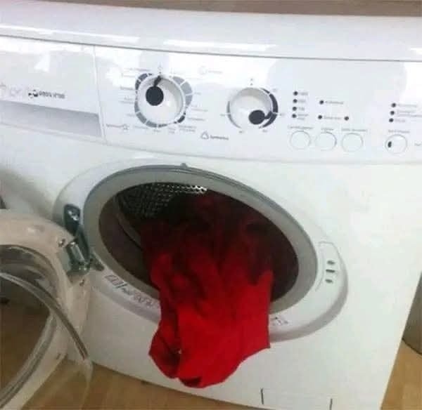 Otvárajúca sa práčka s červenou bielizňou v bubne, pripravená na pranie.