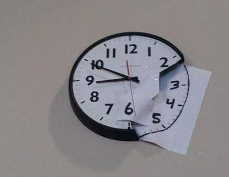 Nástenné hodiny s chýbajúcim číselníkom nahradeným kresleným výrezom hodín na bielom papieri.