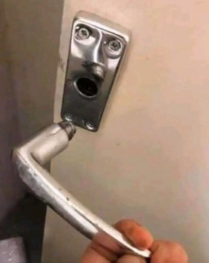 Zlomená kľučka na dverách s uvoľneným mechanizmom, ktorý vyzerá ako prekvapená tvár.