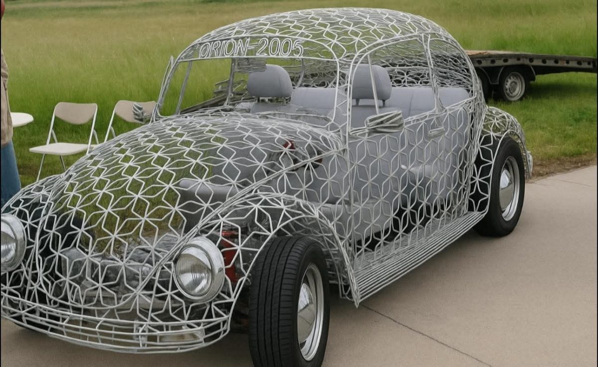 Kovová konštrukcia automobilu v tvare Beetle, bez karosérie, stojí na betónovej ploche vedľa stoličiek.