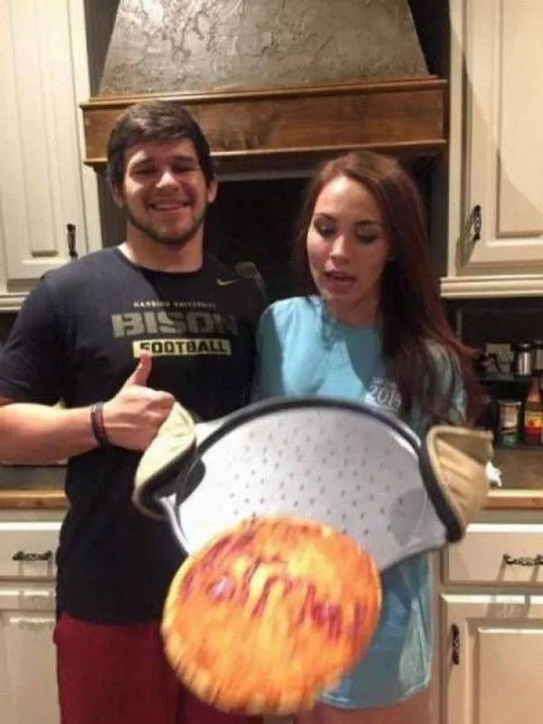 Dvaja ľudia v kuchyni držia plech s jedlom a usmievajú sa.