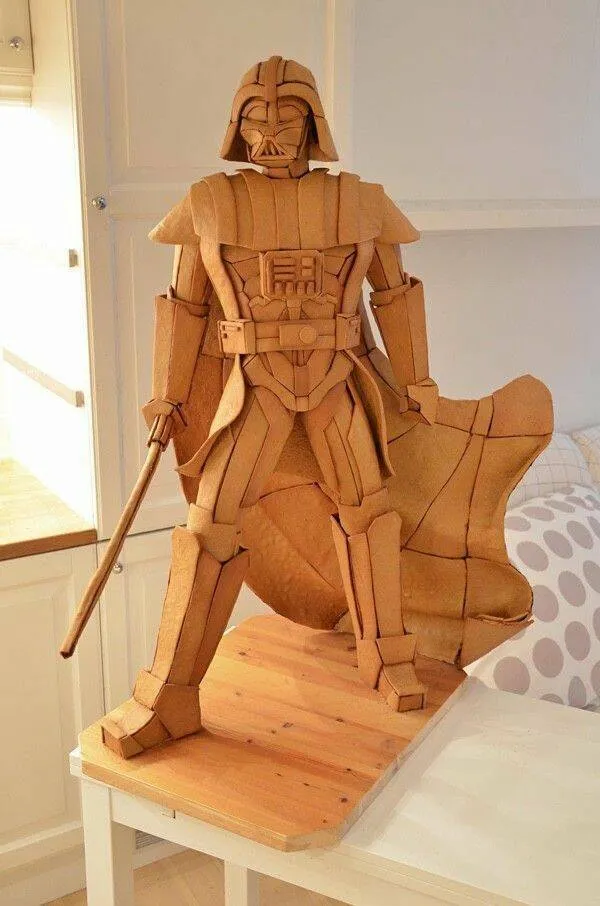 Drevená socha ikonickej postavy z filmu, stojaca na stole v interiéri, s detailmi z preglejky.