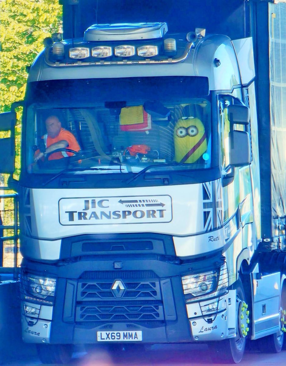 Kamión značky Renault s vodičom a plyšovým maskotom na palubnej doske, označený logom JIC Transport.